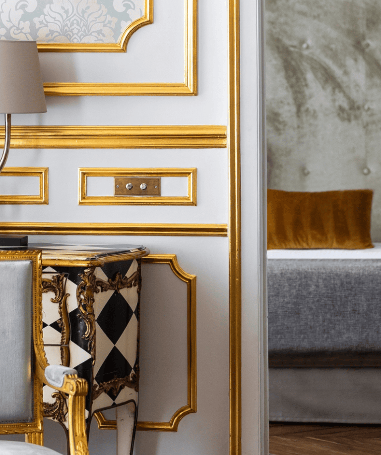 Prunkvolles Zimmer mit Golddekor und historischen Möbeln im Hotel Le Place d'Armes